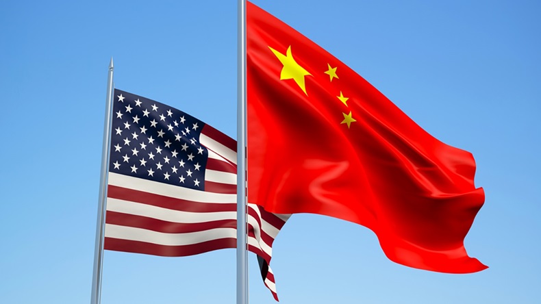 Flags of China and USA fly against blue sky