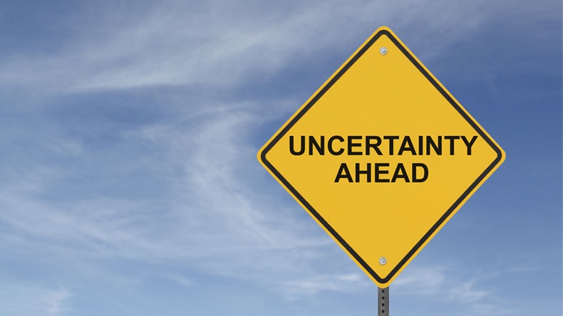 "Uncertainty Ahead” sign on a background of blue sky with clouds 
