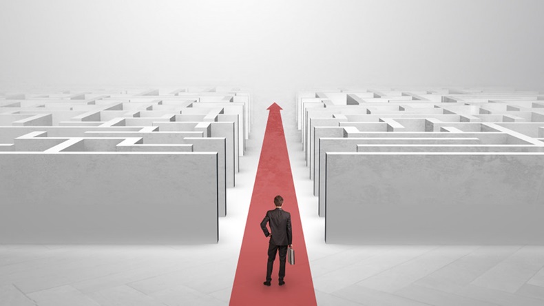 Businessman going straight ahead on a red carpet arrow between two maze