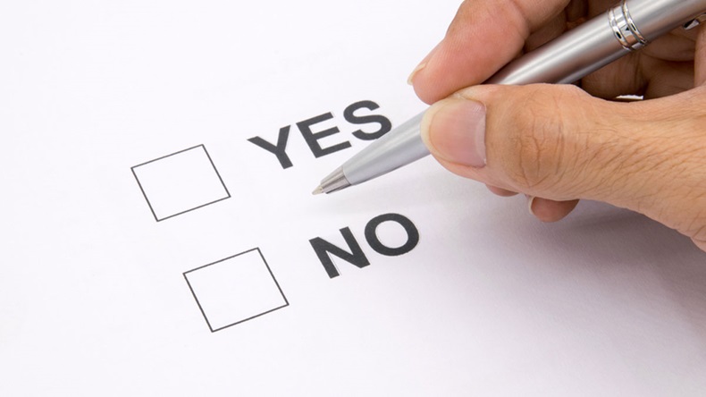 Man hand with pen over document, select Yes or No.