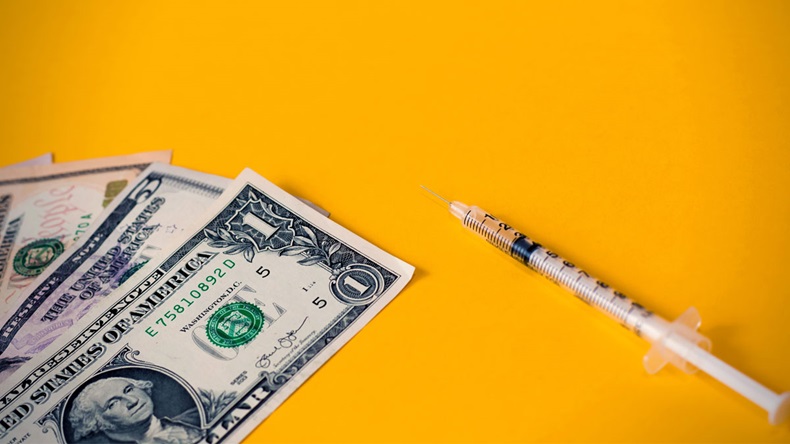 Insulin syringe and dollars money banknotes on a orange background