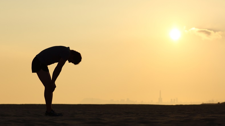 Silhouette of an exhausted sportsman at sunset with the horizon in the background - Image 