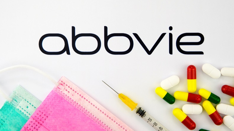 Stone / United Kingdom - February 12 2020: Abbvie biopharmaceutical company logo seen on the brochure with the viral masks, syringe and pills. Concept photo. Selective focus. 