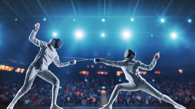 Two female fencing athletes fight on professional sports arena with spectators and lense-flares. Women wear unbranded sports clothes. 