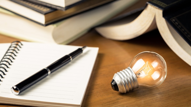 Small light bulb glowing on the desk, with notebook