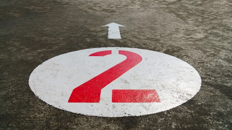 Red number two inside a white circle and an arrow painted on concrete