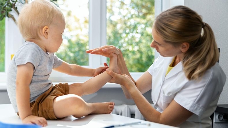 Female orthopedist examining little child's foot condition in clinic.