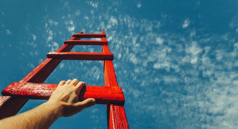 Hand reaching to climb up red, wooden ladder