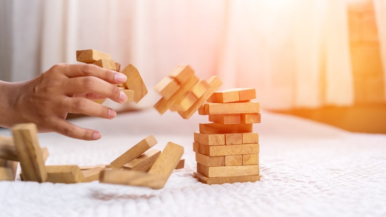 Hand taking wooden blocks out of falling tower of jenga