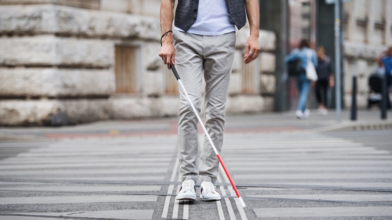 lower half body of blind man walking with stick across road