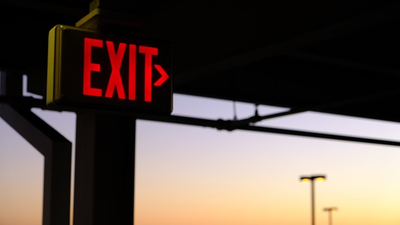 neon red exit sign against sunset sky