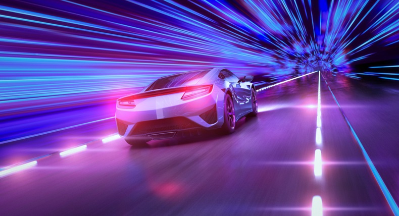 A modern sports car drives quickly through an abstract light tunnel
