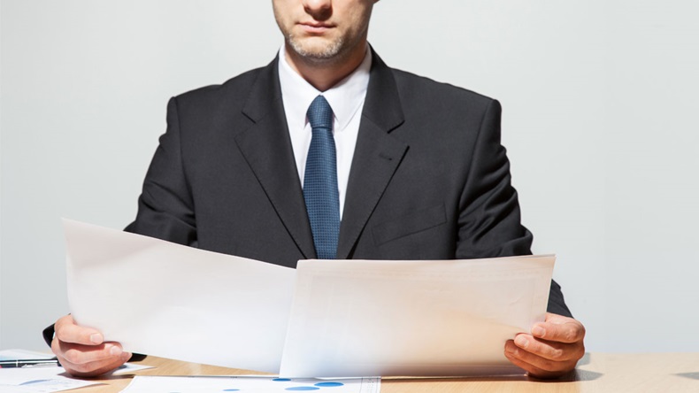 Businessman comparing two documents, neutral background