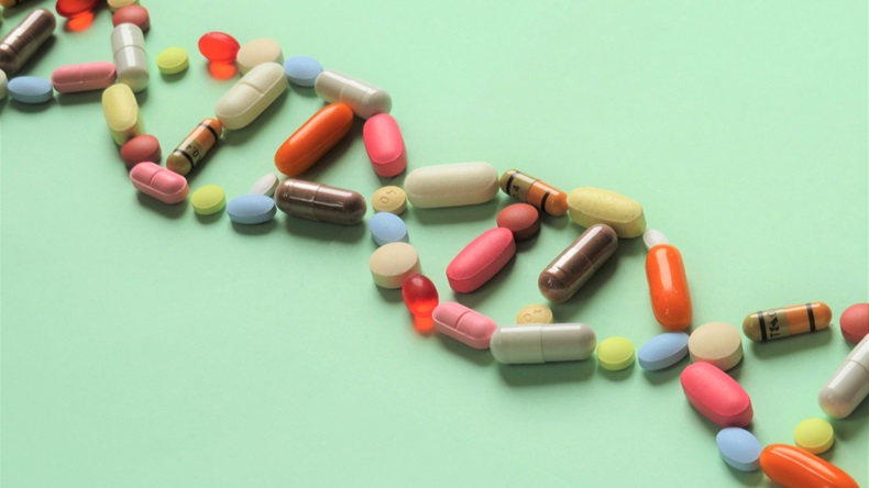 Horizontal image of a collection of prescription capsules and tablets in the shape of DNA running diagonally across the picture on a light green background with room for copy (text).